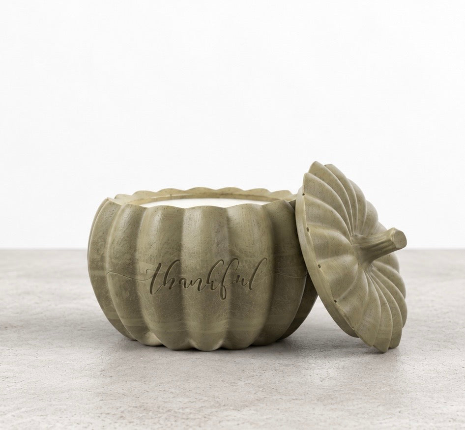 Front view of a pumpkin-shaped concrete candle in smoky olive green, with white wax and Boswellia Candle Co. engraved on the vessel.