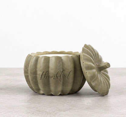 Front view of a pumpkin-shaped concrete candle in smoky olive green, with white wax and Boswellia Candle Co. engraved on the vessel.