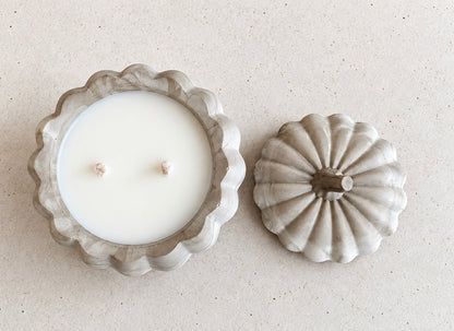 Overhead view of the open pumpkin candle with smooth white wax and two wicks, beside its matching stemmed concrete lid.