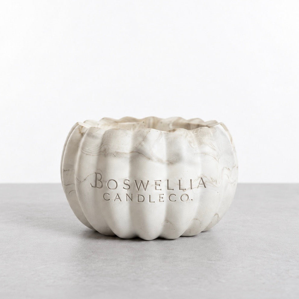Back of the open marbled pumpkin candle vessel, showing the Boswellia Candle Co. logo engraved in the concrete.