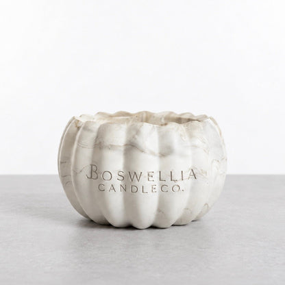 Back of the open marbled pumpkin candle vessel, showing the Boswellia Candle Co. logo engraved in the concrete.