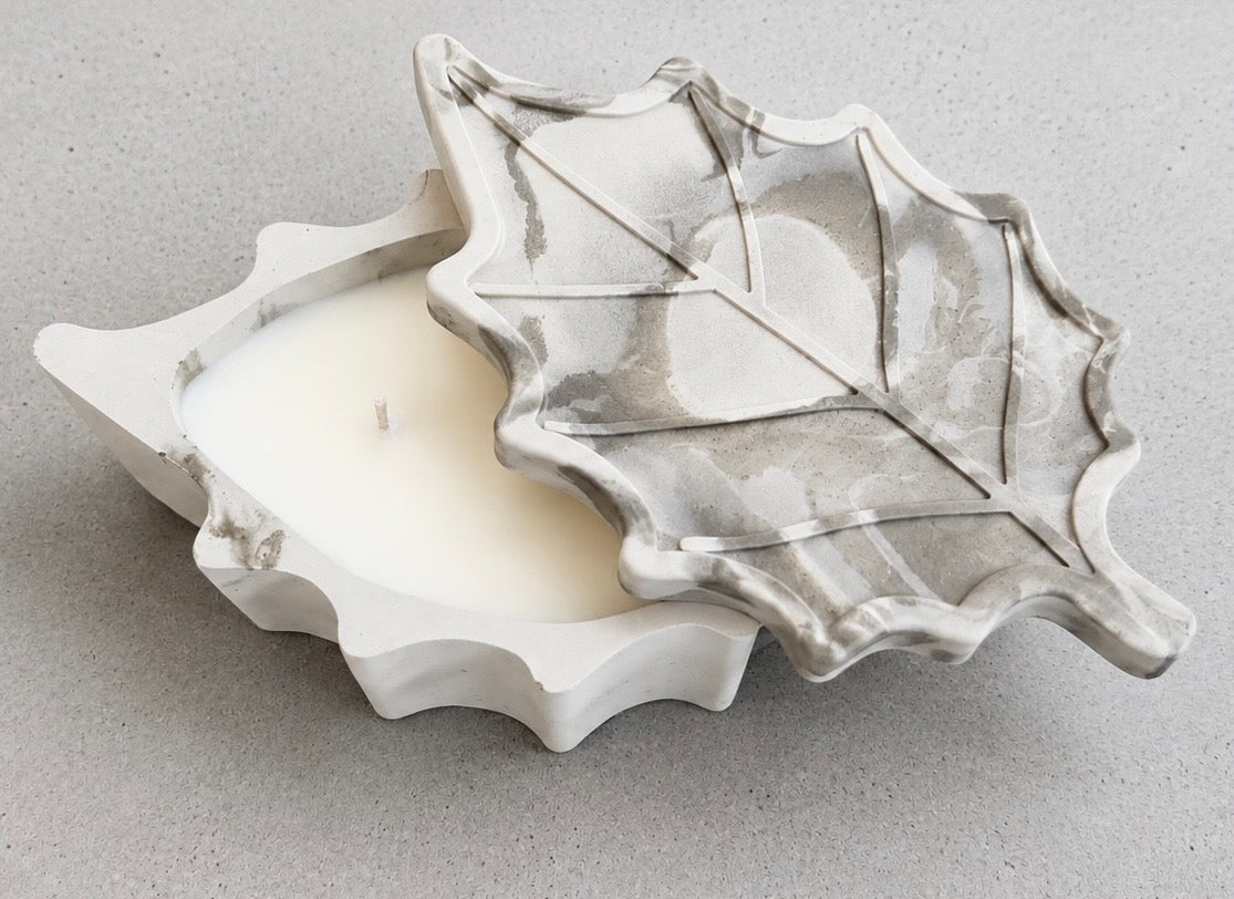 Overhead view of the white and green marbled leaf candle, with its veined leaf-shaped lid partly lifted to reveal the white wax inside.