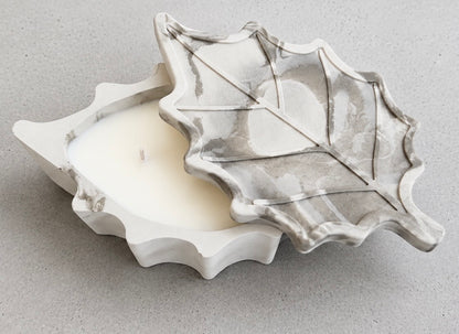 Overhead view of the white and green marbled leaf candle, with its veined leaf-shaped lid partly lifted to reveal the white wax inside.
