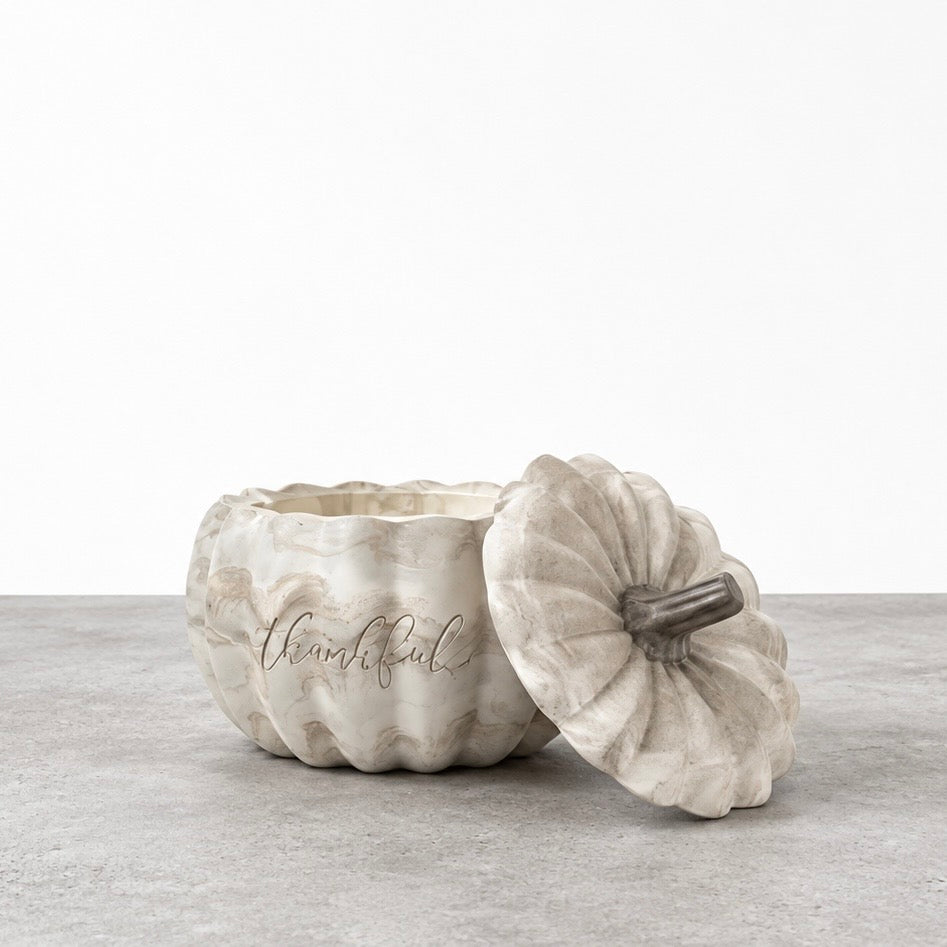 Open Thankful pumpkin candle in a marbled concrete vessel, with its matching stemmed lid leaning against the front.