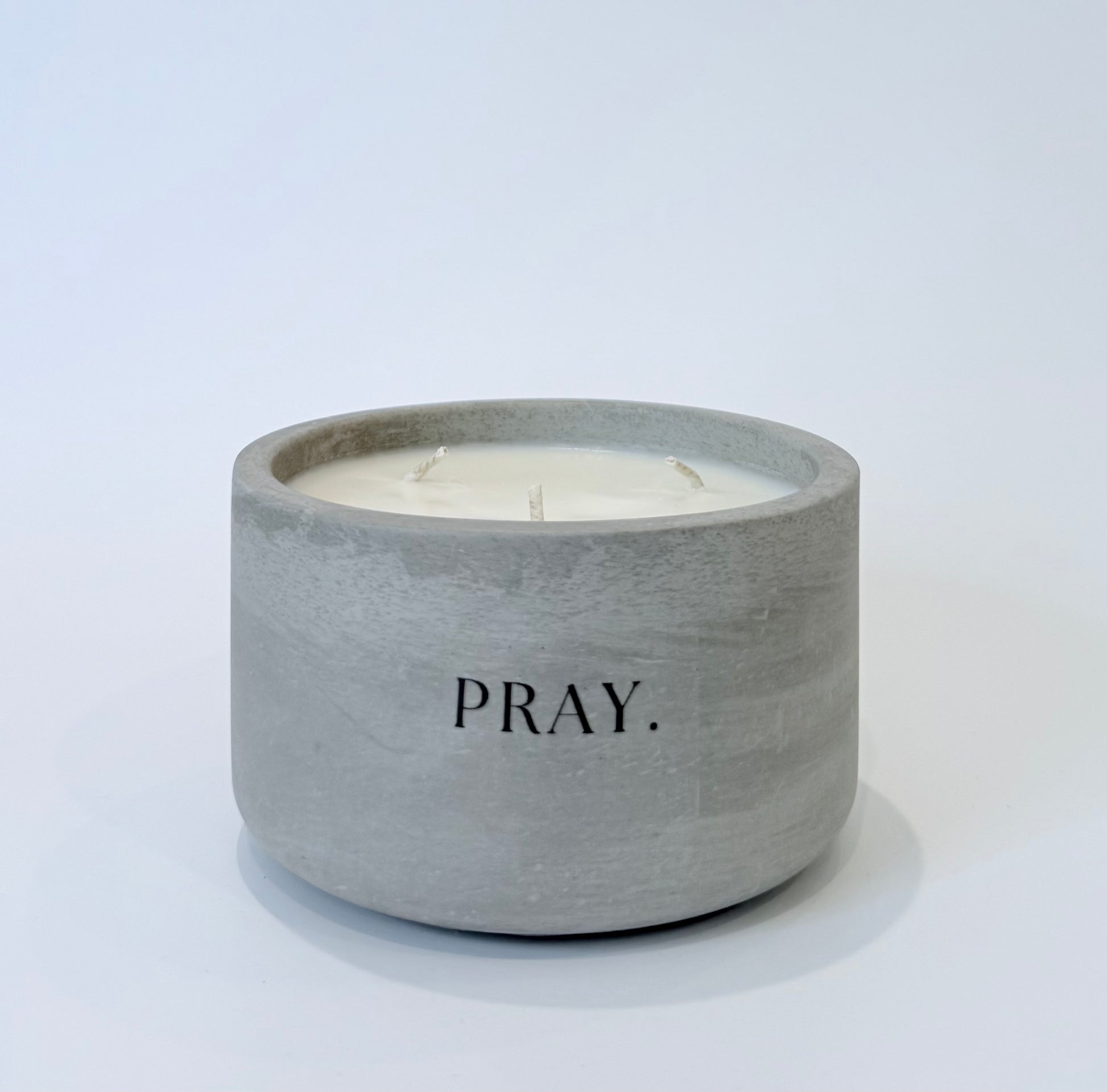 Pray soy candle in gray concrete vessel on white background
