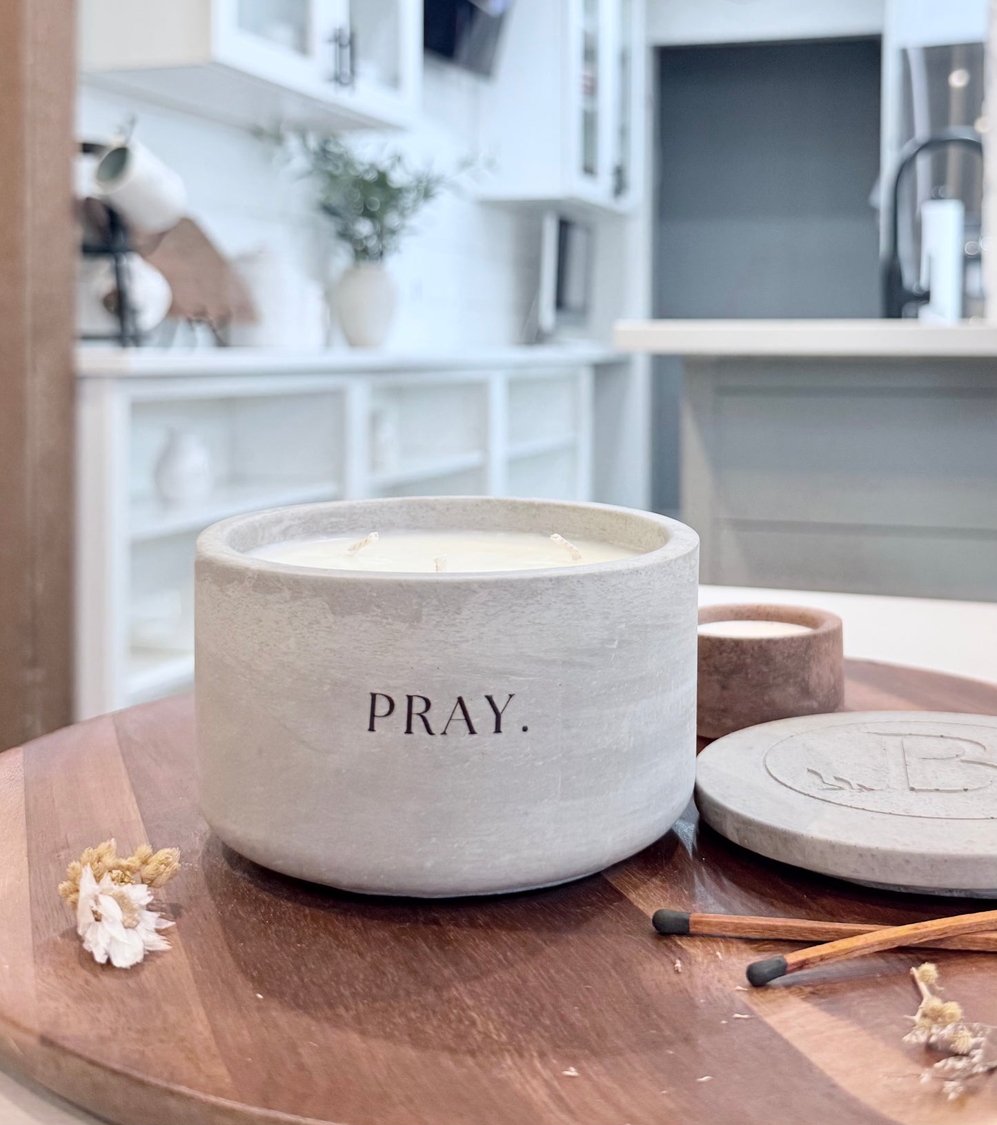 Christian candle with Pray message on wooden table, gray concrete soy candle with lid in home setting