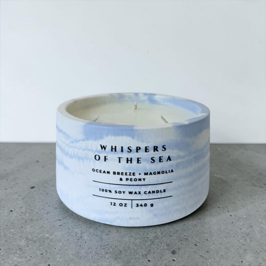 Whispers of the Sea soy candle in blue marbled concrete vessel with ocean breeze magnolia and peony scent