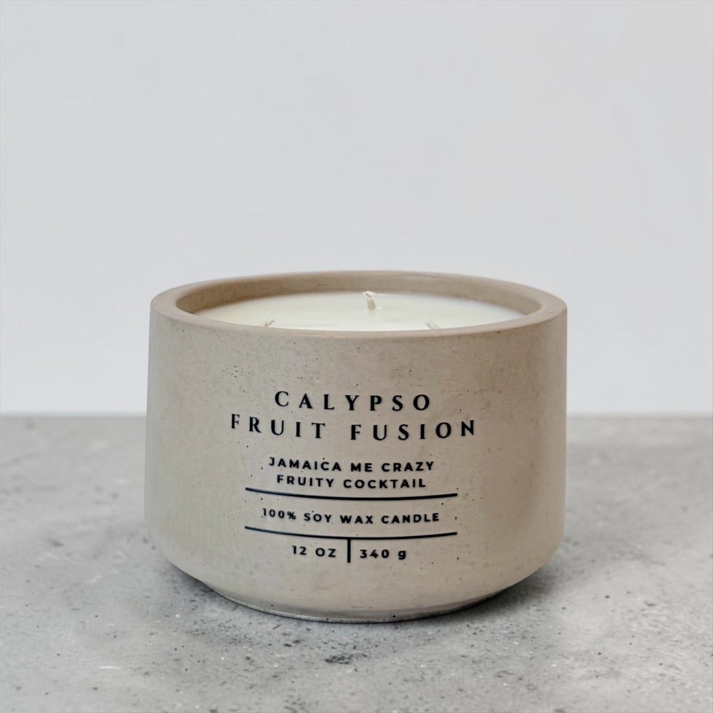 Calypso Fruit Fusion soy candle in beige concrete vessel with tropical fruity scent on gray background
