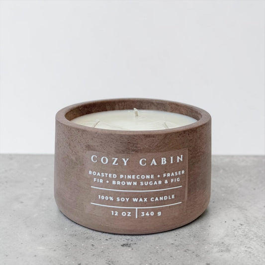 Cozy Cabin soy candle in brown concrete vessel with pine, fir and brown sugar scent on gray background