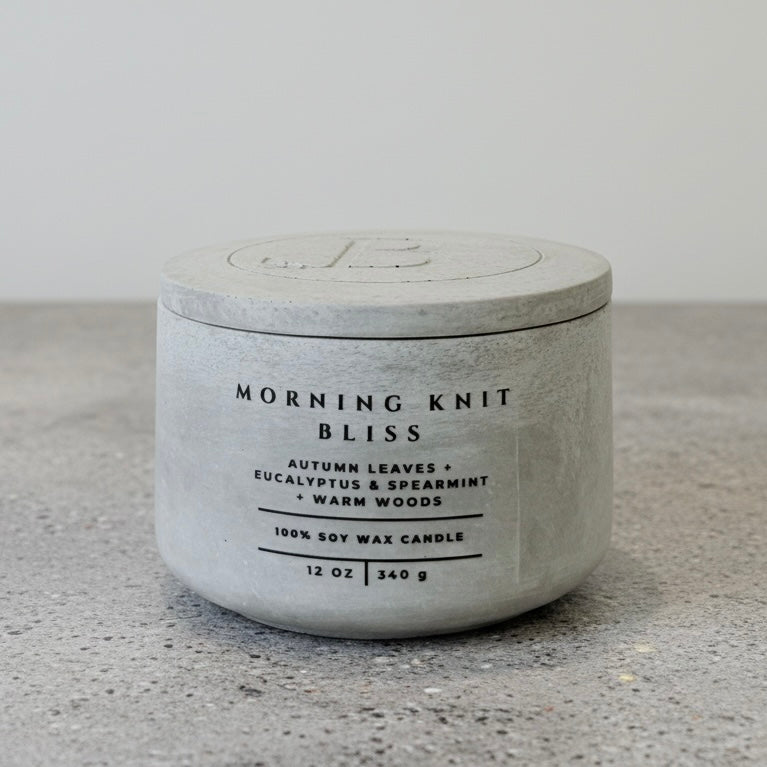 Morning Knit Bliss luxury soy wax candle with engraved concrete lid and handcrafted vessel, scented with autumn leaves, eucalyptus, spearmint, and warm woods.
