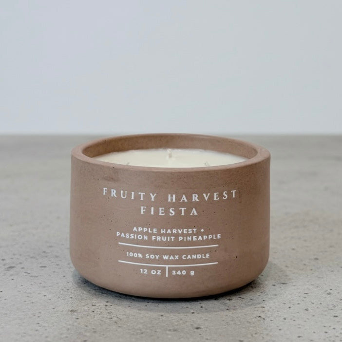 Fruity Harvest Fiesta tropical soy wax candle in a handcrafted concrete vessel, featuring apple harvest, passion fruit, and pineapple fragrance notes. Faith-inspired gift by Boswellia Candle Co.