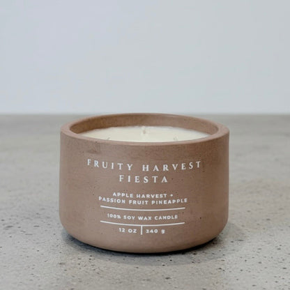 Fruity Harvest Fiesta tropical soy wax candle in a handcrafted concrete vessel, featuring apple harvest, passion fruit, and pineapple fragrance notes. Faith-inspired gift by Boswellia Candle Co.