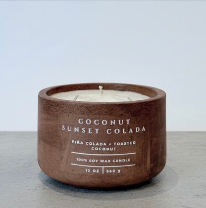 Open Coconut Sunset Colada Scripture Candle, 12 oz soy wax candle in a handcrafted concrete vessel with tropical piña colada and toasted coconut fragrance notes.
