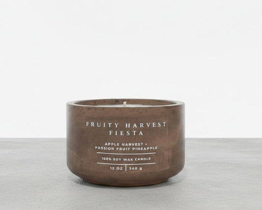 Fruity Harvest Fiesta tropical soy wax candle in a handcrafted concrete vessel, featuring apple harvest, passion fruit, and pineapple fragrance notes. Faith-inspired gift by Boswellia Candle Co.